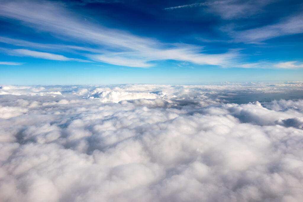 Blue sky and sunshine above a dense layer of white clouds