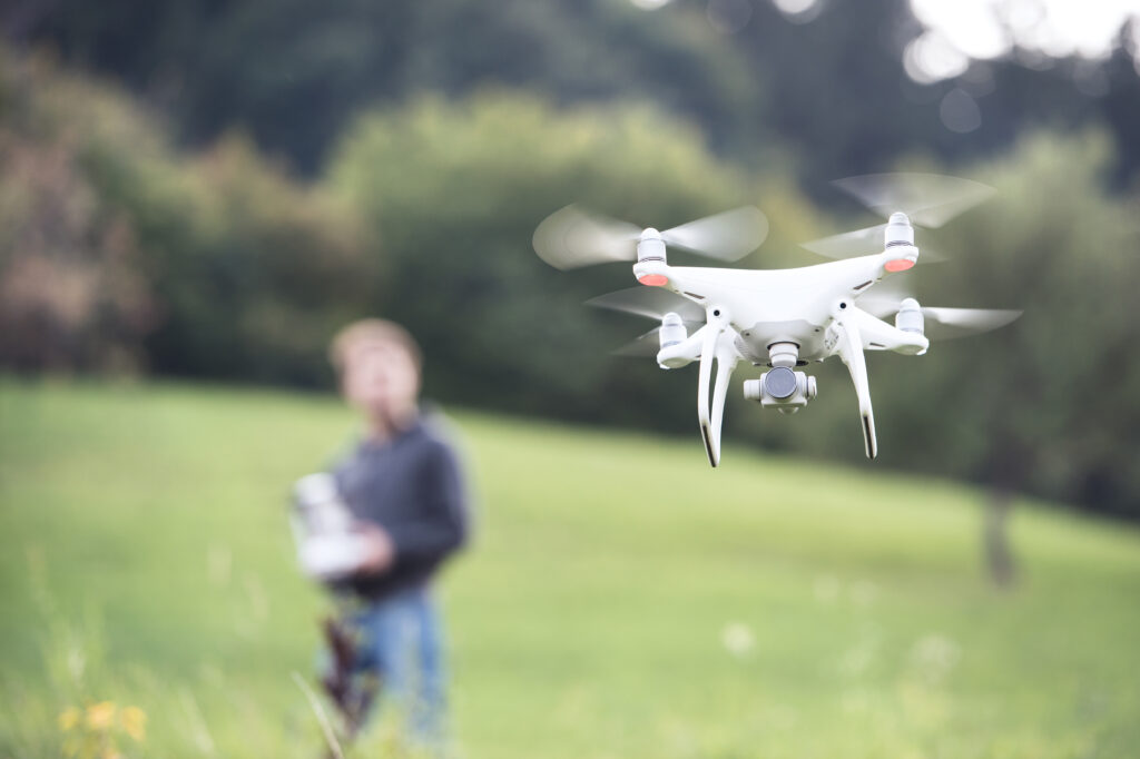 Quadcopter drone hovering in grassy field.